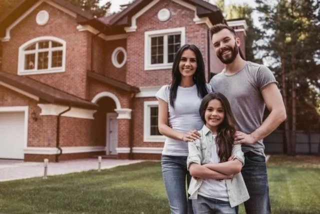 A family standing before their home with new shingles