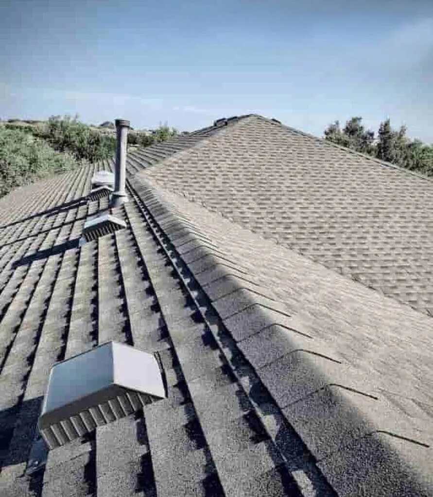 A residential roof with a chimney and smokestack in Hutto