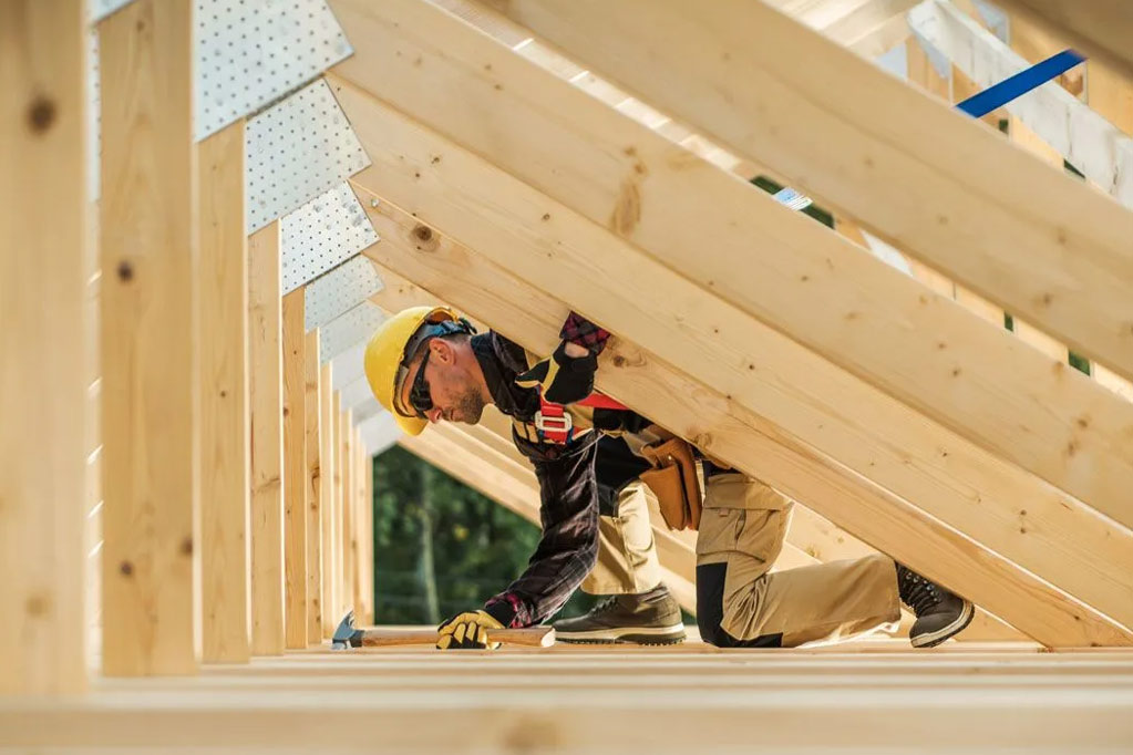 A person in a hard hat holding a hammer for roof installation