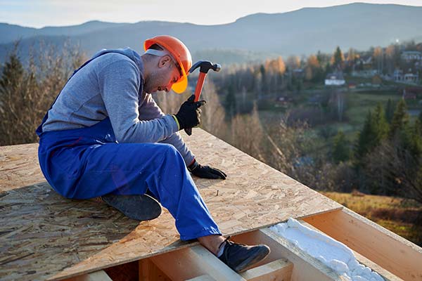 A person sitting on a roof with a hammer in Buda